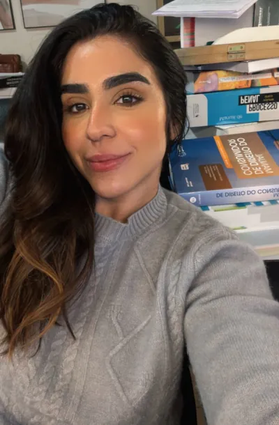 Selfie de Maria Lívia em seu quarto com estante de livros ao fundo